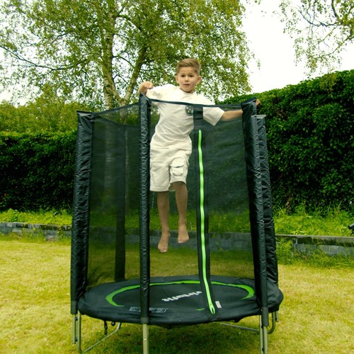 Lifestyle afbeelding van een springend kind op de zwarte VirtuFit kindertrampoline van 140 cm in een groene tuin setting.