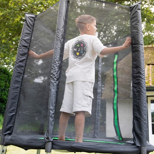 Zijaanzicht in lifestyle setting van een kind op de zwarte VirtuFit kindertrampoline met rondom een fijnmazig veiligheidsnet voor optimale bescherming.